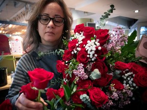 A woman adds a rose to a bouquet of red and white flowers.