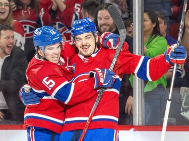 Montreal Canadiens Alex Newhook and Arber Xhekaj embrace in celebration as fans cheer behind them