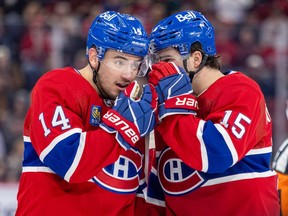 Montreal Canadiens Nick Suzuki, left, and Alex Newhook shield their mouths while discussing