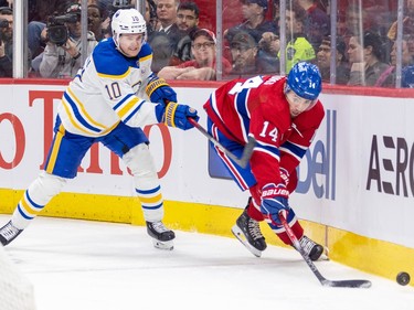 Montreal Canadiens' Nick Suzuki takes a stick to the arm from Buffalo Sabres' Henri Jokiharju