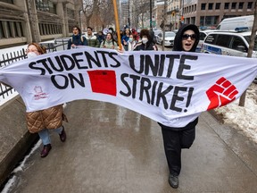 Protesting students hold a sign reading Students Unite on Strike.