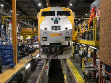 A yellow and grey Via locomotive sits in a maintenance bay