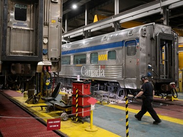 A worker walks between two train cars in a maintenance building