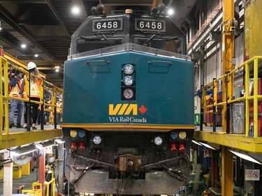 A green Via locomotive sits in a maintenance bay
