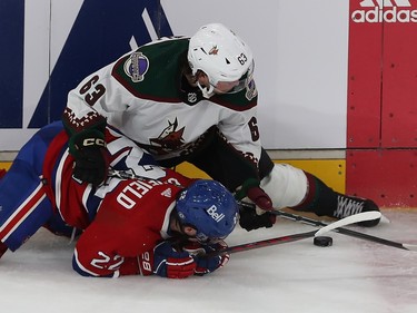 Montreal Canadiens' Cole Caufieldlies on the ice underneath Arizona Coyotes' Matias Maccelli