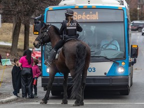 A police officer on horseback blocks the route of a city bus.