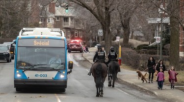 Two police officers on horseback ride by a city bus.