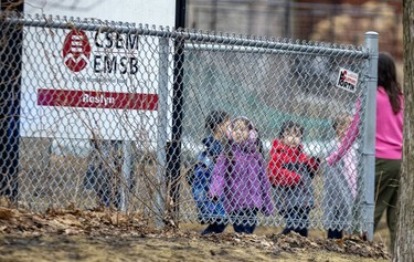 A metal fence stands in front of a sign reading CSEM, EMSB, Roslyn. Young children are seen behind the fence.