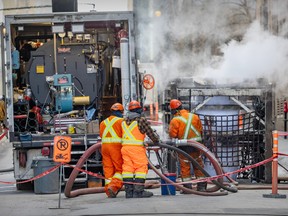 Workers monitor the installation of a liner, right, into the sewer under de la Gauchetière St. between Bleury St. and Beaver Hall Hill in Montreal on Thursday, Feb. 29, 2024.