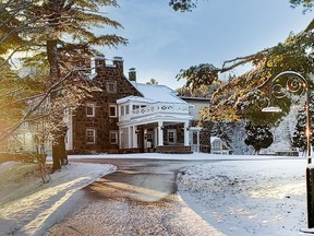 A view of a brick mansion covered in snow, with a winding driveway leading to it.
