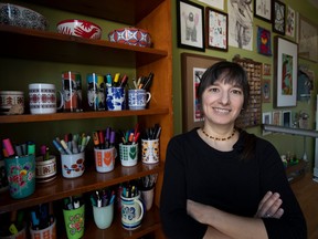Montreal author and cartoonist Elise Gravel stands in front of a bookshelf filled with mugs and cups holding markers and drawing implements.