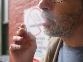 Side view of a man smoking. There is a no-smoking sign behind him.