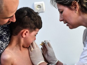 father holds child getting a shot