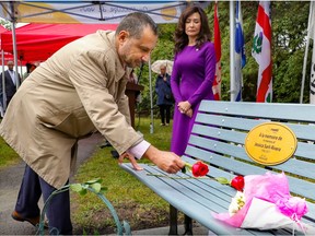 A man places a rose on a commemorative bench in honour of his daughter, who was killed in an alcohol-related road incident. His wife looks on in the background.