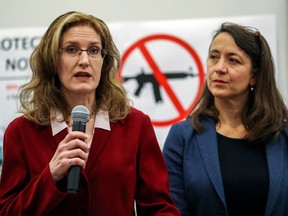 École Polytechnique massacre survivors Heidi Rathjen and Nathalie Provost stand in front of a sign with a crossed-out gun on it. Rathjen is speaking into a microphone.
