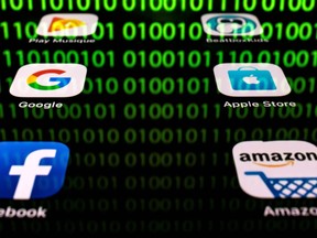 In this file illustration picture taken on April 20, 2018 in Paris shows apps for Google, Amazon, Facebook, Apple (GAFA) and the reflexion of a binary code displayed on a tablet screen.