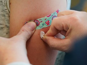 Closeup of a child's arm being swabbed after receiving measles vaccine.