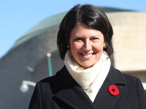 Profile of a woman wearing a white scarf and a poppy on her black coat.