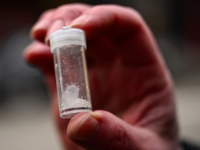 A hand holds a vial with meth.