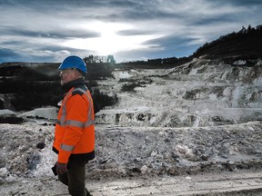 A man in an orange safety vest walks though an open-pit mine