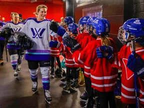 Kids line up to exchange glove taps with Marie-Philip Poulin of PWHL Montreal at teh NHL all-star festivities this month.
