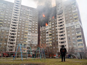 A law enforcement officer stands next to a residential building, damaged as a result of a missile attack in Kyiv on Feb. 7, 2024, amid the Russian invasion of Ukraine.