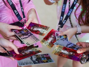A picture of hands in a circle holding Taylor Swift tickets.