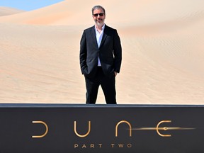 Denis Villeneuve stands behind a sign reading 'Dune Part Two' in the desert