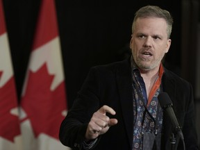 Mark Holland speaks in a room with Canadian flags behind him