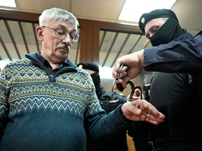 A police officer puts handcuffs on Oleg Orlov, the 70-year-old human rights campaigner and co-chair of the Nobel Prize winning Memorial group, after Orlov was sentenced to two and a half years in jail on charges of repeatedly "discrediting" the Russian army, in Moscow on Feb. 27, 2024.