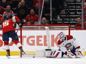 Anton Lundell #15 of the Florida Panthers follows through on a shot while Canadiens goaltender Samuel Montembeault, on one side of the net, looks behind him to see the puck inside it