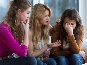Two young worried girls supporting crying friend