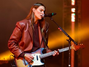 A woman singing on stage while playing the electric guitar