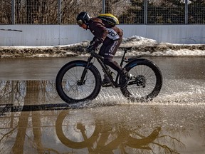A person rides a bike through a huge puddle.