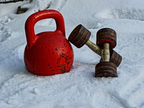 An old red weight and a pair of dumbbells in the snow.