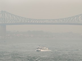 A boat is seen near the Jacques-Cartier Bridge obscured by smog in Montreal on June 25, 2023.