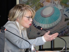 Quebec Tourism Minister Caroline Proulx gestures as she stands at a microphone in front of a picture of Montreal's Olympic Stadium.