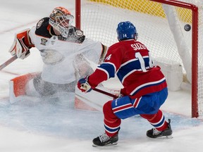 Canadiens' Nick Suzuki has his stick on the ice and redirects a pass past Ducks goaltender Lukas Dostal.