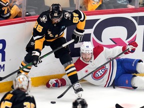 Montreal Canadiens' Joel Armia lies on the ice along the boards but tries to play the puck with his stick underneath Pittsburgh Penguins player Erik Karlsson