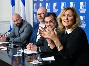 Five people sit at a table during a news conference