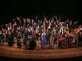 Dozens of people are seen on stage at an orchestra.