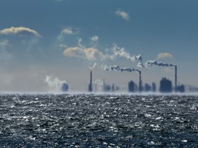 Smokestacks in the distance shimmer in the cold waves over Lake Ontario in Toronto, Friday, Feb. 3, 2023.