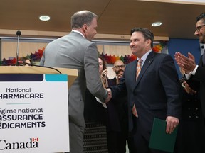 Minister of Health Mark Holland, left, shakes hands with NDP MP for Vancouver Kingsway Don Davies during a press conference about new national pharmacare legislation, in Ottawa on Thursday, Feb. 29, 2024.