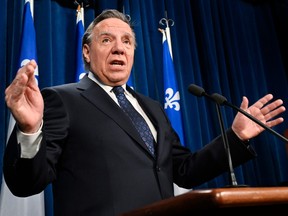 Quebec Premier François Legault gestures with his hands at a podium during a news conference.