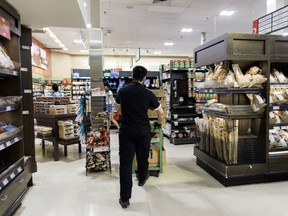 A worker pushes a cart inside a grocery store in Toronto, Tuesday, July 18, 2023.