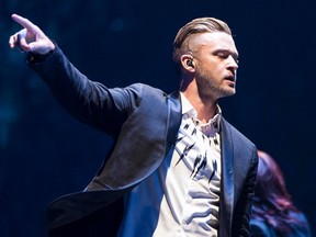 Justin Timberlake is seen from the waist up, wearing a blazer over a t shirt, pointing to the left side of the screen.