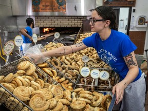 A worker in a bagel shop sorts bagels, including a variety with no hole.