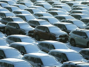 Snow covered vehicles sit in a parking lot