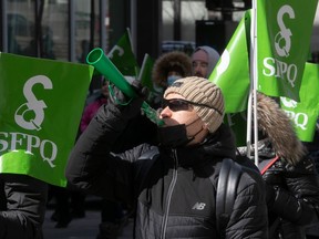 A man blows into a green plastic horn amid green SFPQ flags