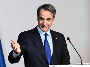 Kyriakos Mitsotakis gestures while speaking at a podium